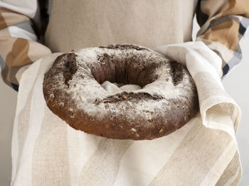 The chef holds traditional sourdough bread loaf with sunflower seeds. side view. close-up.