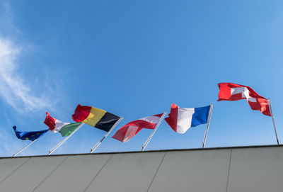 Low angle view of flags against clear blue sky