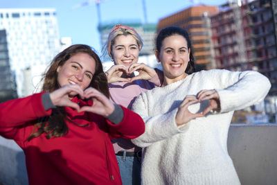 Portrait of smiling women forming heart shapes