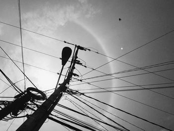 Low angle view of silhouette bird on cable against sky