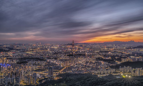 Illuminated cityscape against sky at sunset