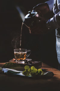 Midsection of man pouring herbal tea on table