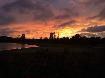 Scenic view of lake against cloudy sky during sunset