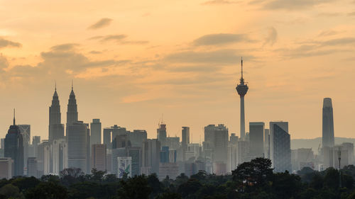 Modern buildings in city against sky during sunset