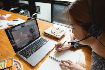 Woman using phone while sitting on table