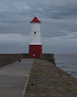 Lighthouse by sea against sky