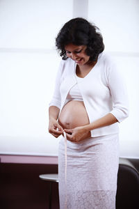 Pregnant woman measuring belly at home