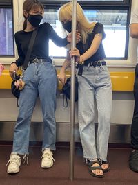 Full length of women wearing mask standing in train