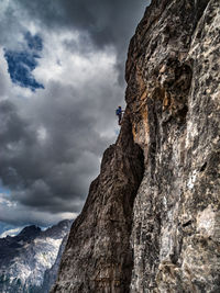 Low angle view of person on rock against sky