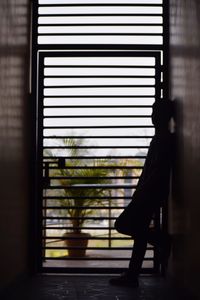 Side view of silhouette man standing by metal gate