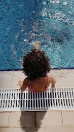 High angle view of a little girl sitting on swimming pool