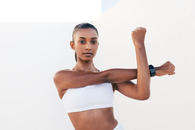 Portrait of young woman exercising against white background