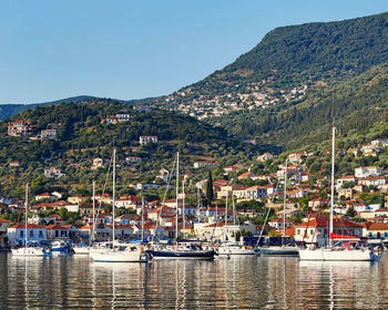 Sailboats moored in harbor by buildings against clear sky