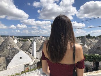 Rear view of woman looking at city buildings against sky