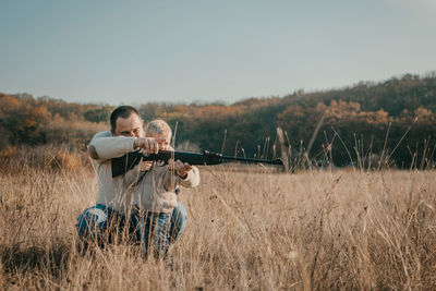 Men sitting on land by land against sky