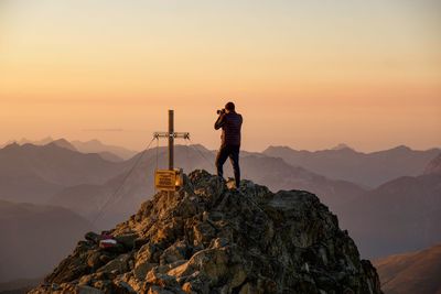 Man standing on rock against mountain during sunset
