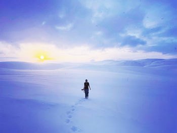 Rear view of woman walking into seemingly endless icy winter landscape 