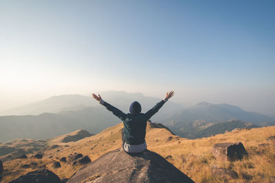 Man with arms outstretched against mountain range