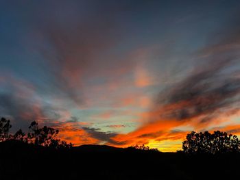 Scenic view of silhouette mountains against orange sky