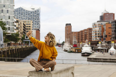 Happy woman taking selfie through smart phone at elbphilharmonie in hafencity