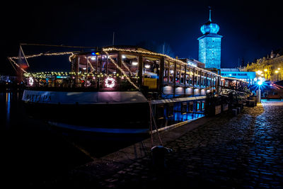 View of illuminated boats moored at river