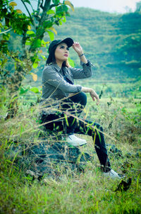 Side view of woman sitting on field