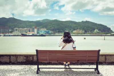 Girl sit on bench look at harbour view and sky