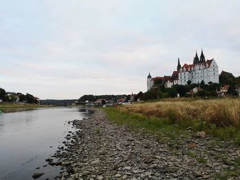 Buildings by river against sky in city