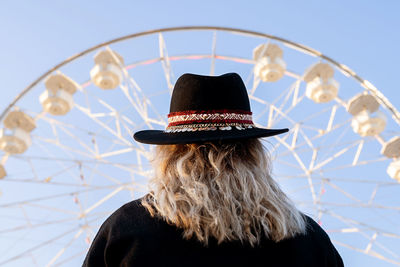 Rear view of woman in amusement park against sky