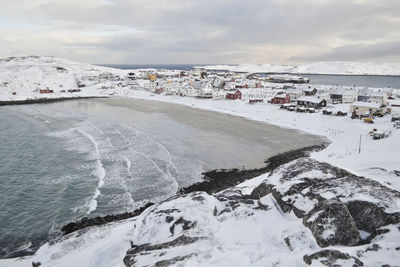 Houses by sea against sky during winter