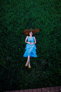 Full length portrait of young woman lying on field