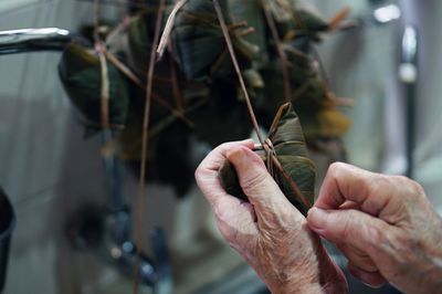 Cropped image of person tying banana leaf