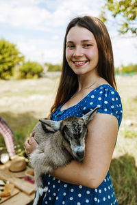 Portrait of smiling young woman standing against trees