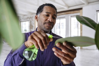 Man spraying water on leaf in office