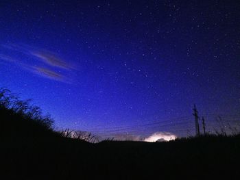 Low angle view of silhouette landscape against star field