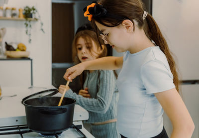 Two children are preparing pasta and preparing a treat.