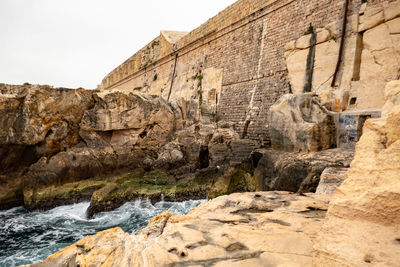 The waves crash on the rocky coast and forterss in malta
