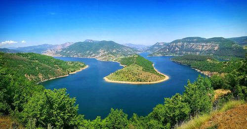 Scenic view of green mountains against blue sky