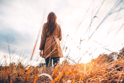 Rear view of woman standing on field against sky