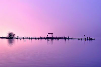 Pier over lake against sky during sunset