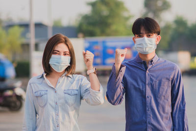 Portrait of couple gesturing while wearing mask standing outdoors