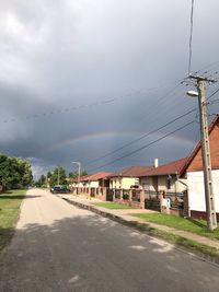 Road by buildings in city against sky
