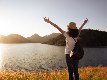 Rear view of woman standing by lake