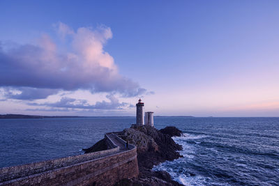 Lighthouse by sea against sky