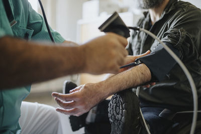 Doctor checking blood pressure of patient with disability in clinic