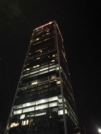 Low angle view of illuminated skyscraper against sky at night