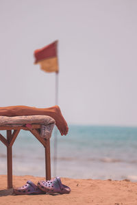 Deck chairs on beach against sky