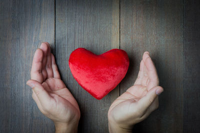 Close-up of hand holding red heart shape decoration on table