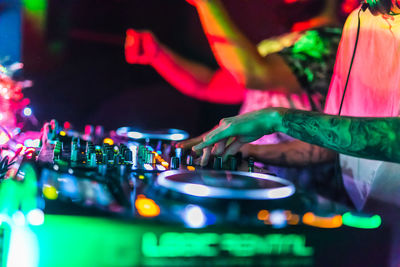 Cropped hand of man with illuminated audio equipment at night