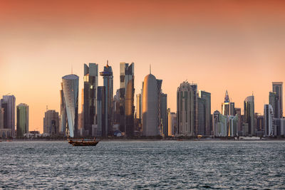 Modern buildings in city against sky during sunset